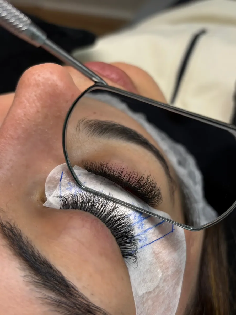 Cliente vendo o próprio olho no espelho durante o atendimento no Studio Crystal Lashes
